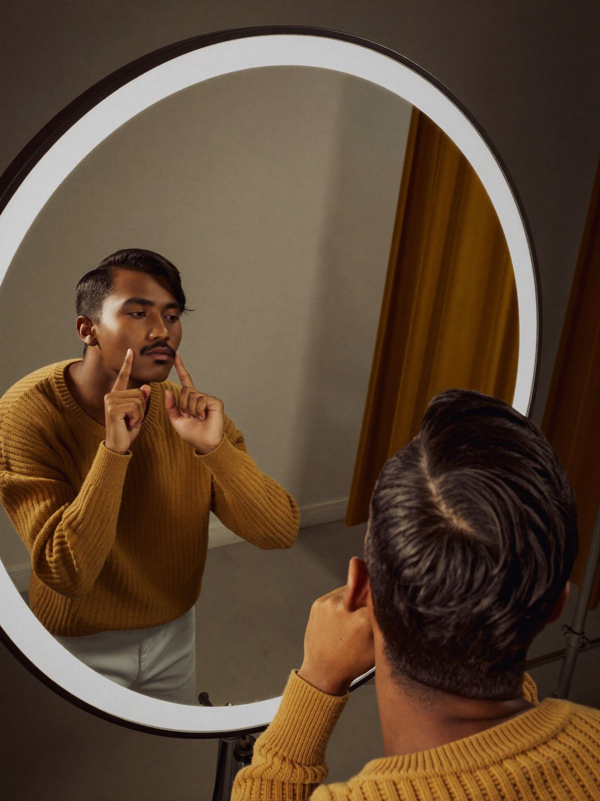 A model practising expressions in a ring-lit mirror
