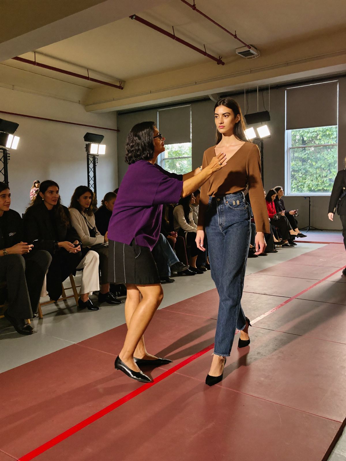 A coach guiding a model through a runway rehearsal