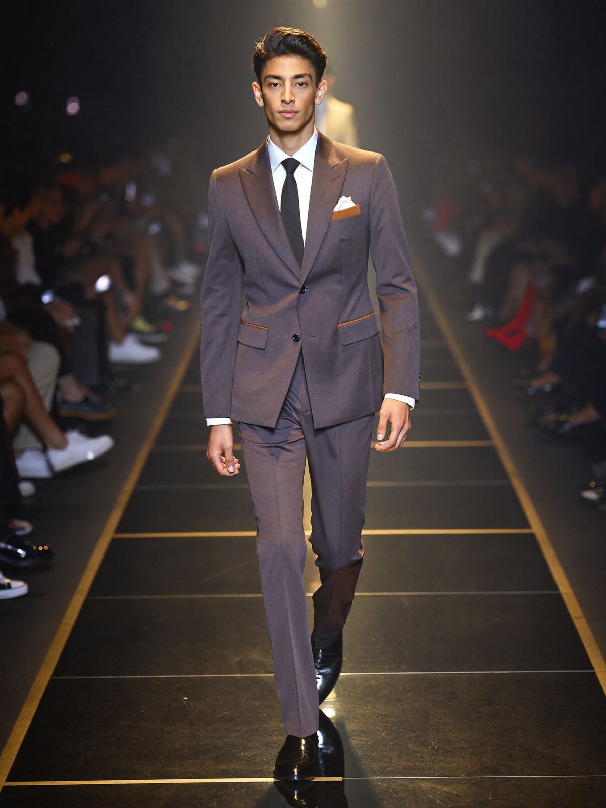 A male model in a brown suit on the runway